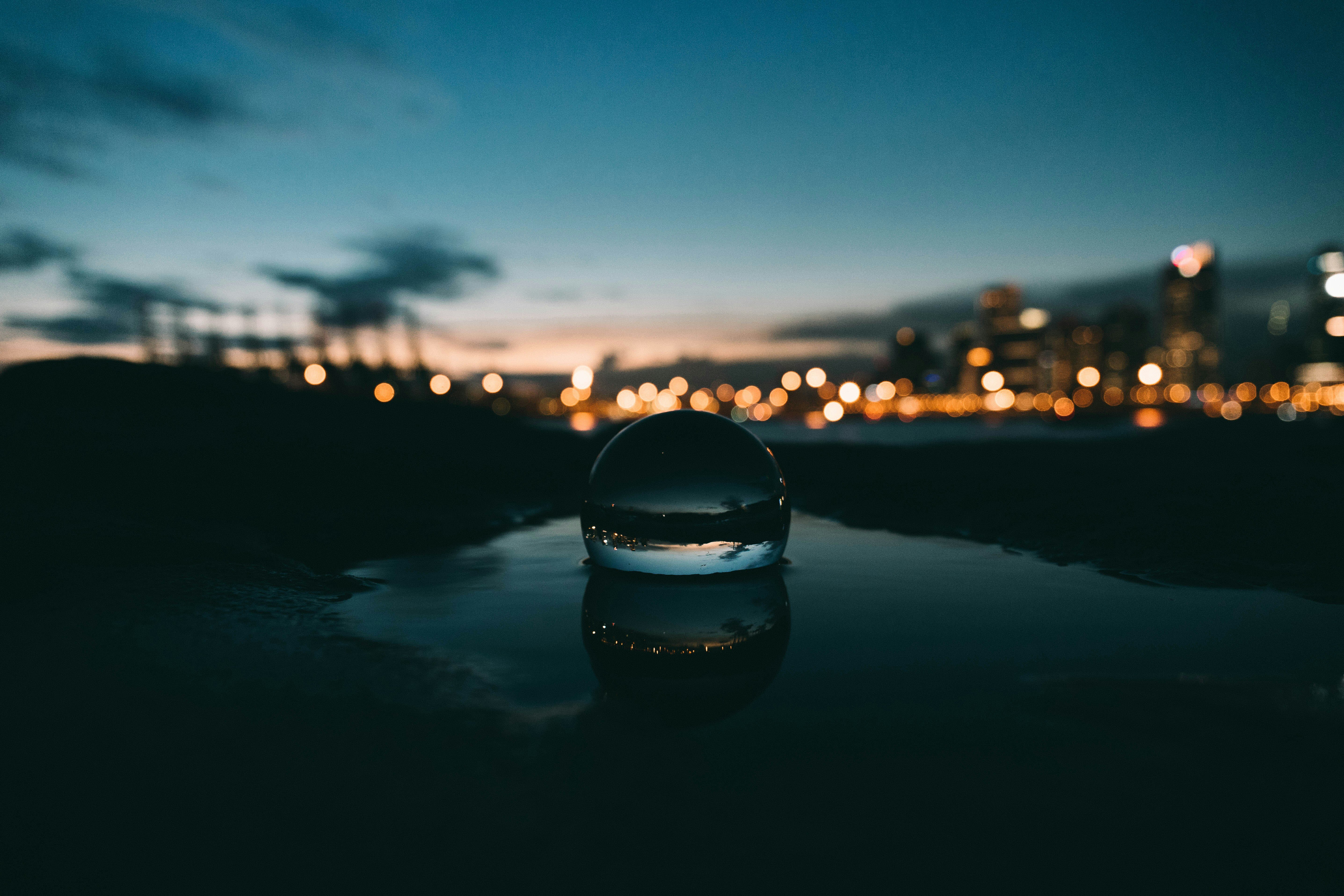 Crystal ball in a puddle beside a river overlooked by buildings and apartments