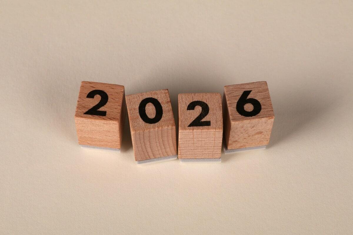Four wooden blocks arranged to spell out the year "2026" against a neutral cream background.