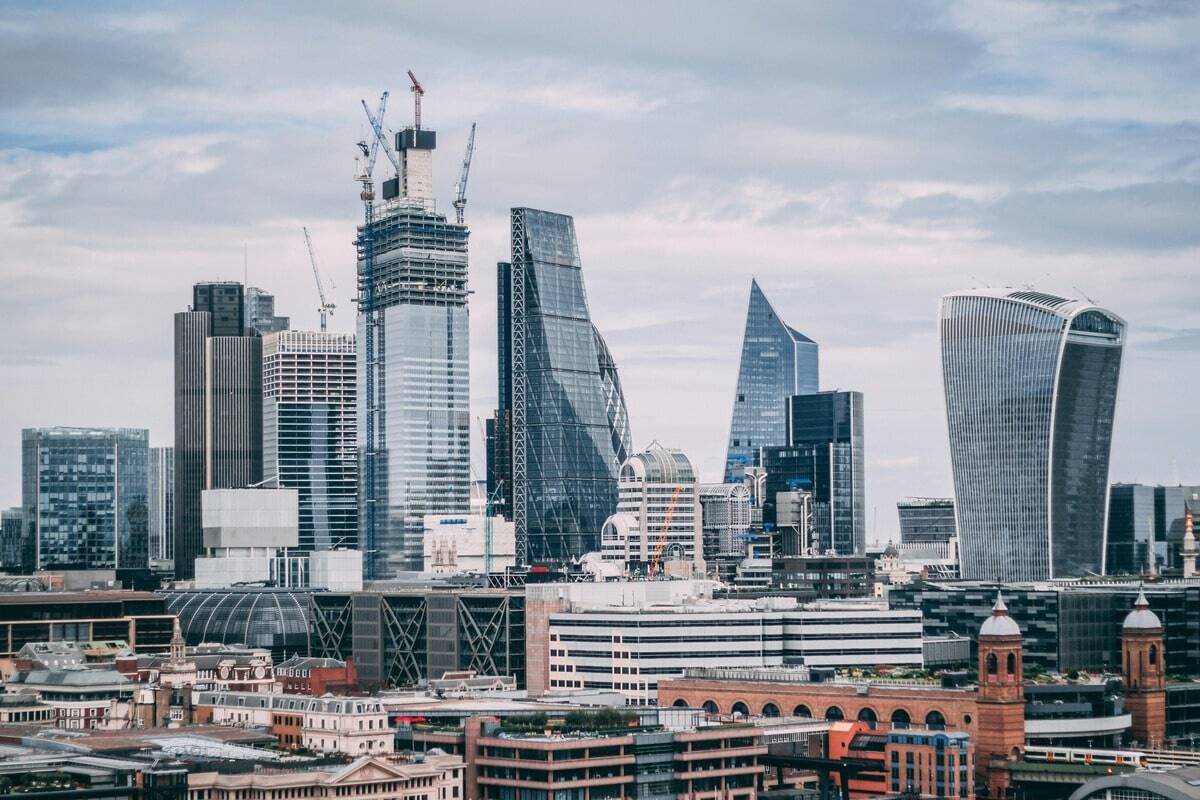 Skyline of the City of London featuring modern skyscrapers including the Walkie Talkie building, the Leadenhall Building (Cheesegrater), and other contemporary high-rise structures under construction, set against a cloudy sky.