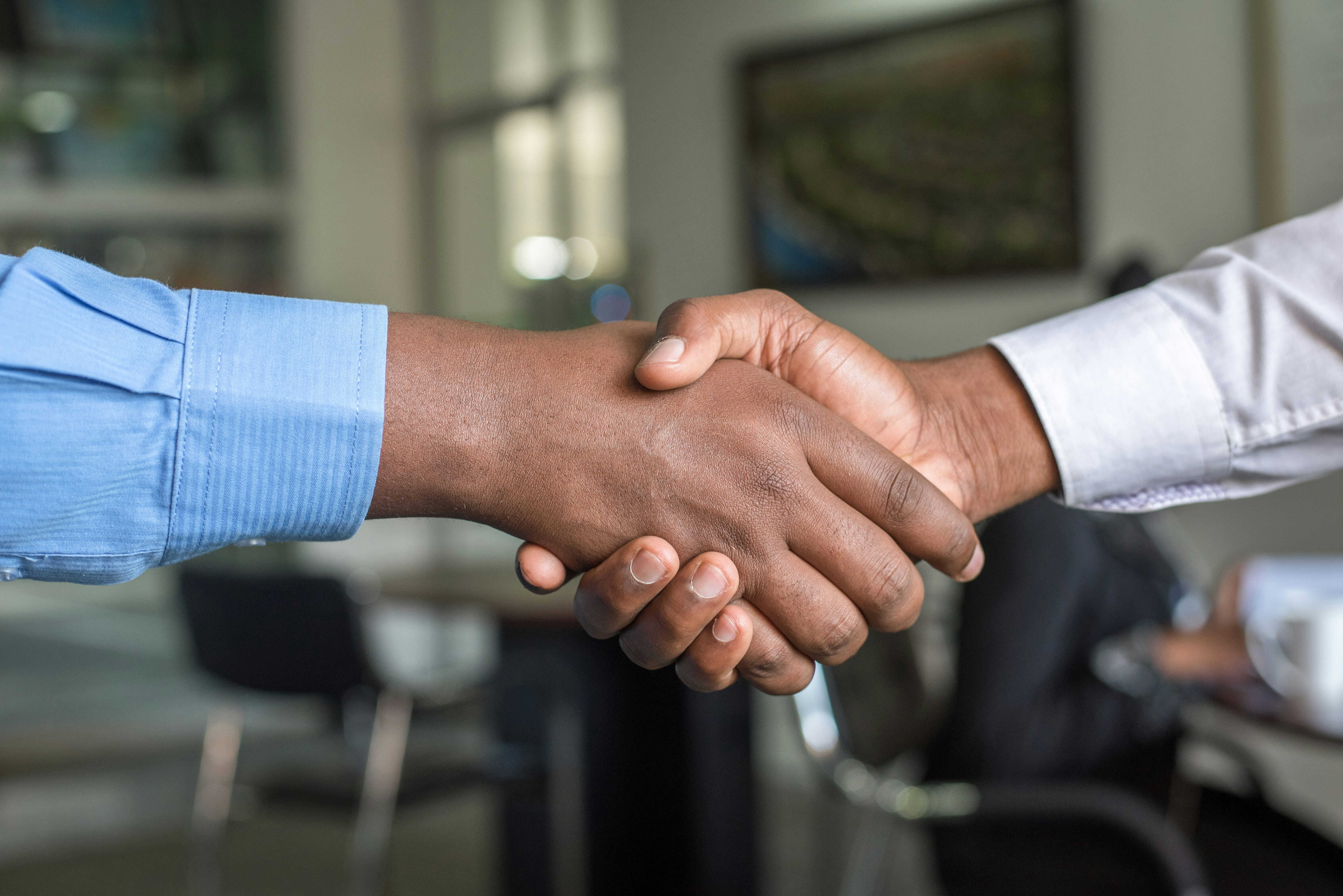Two hands shaking in an office environment. 