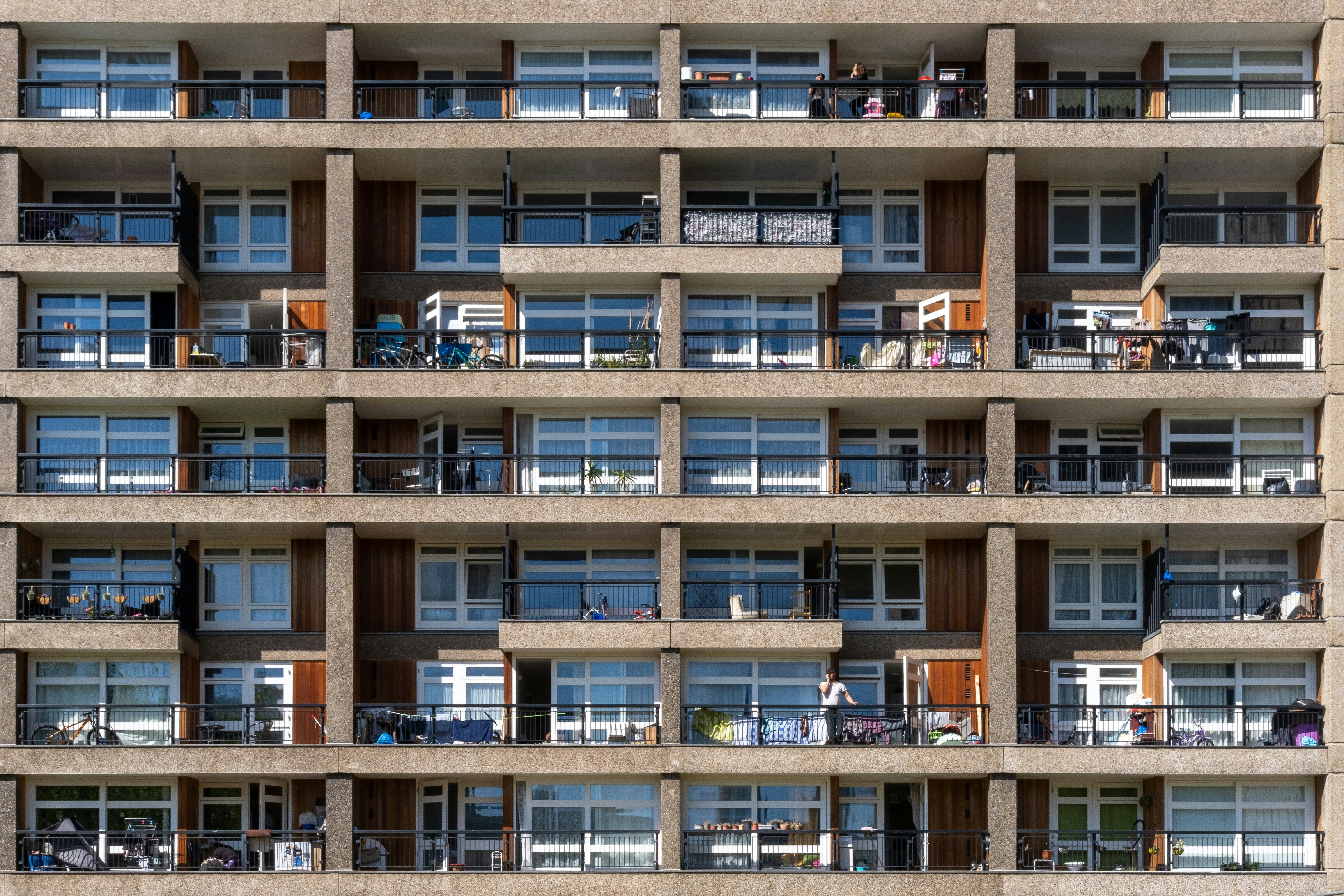 A block of tightly packed flats in a tower block in East London. There are washing lines, bikes and people on some of the balconies. 